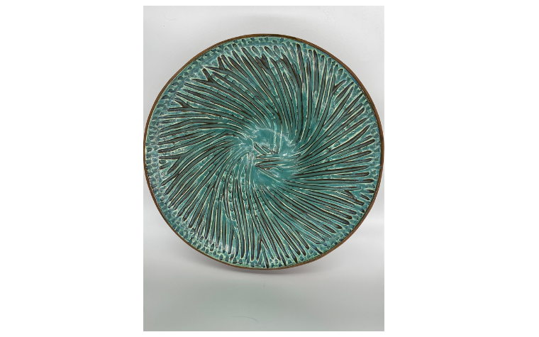 A glazed plate with an intricate handmade pattern.